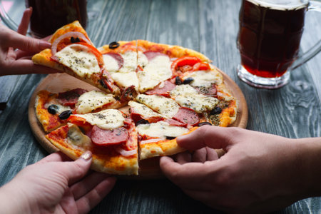 Company of friends eating homemade pizza and drinking dark beer,の写真素材