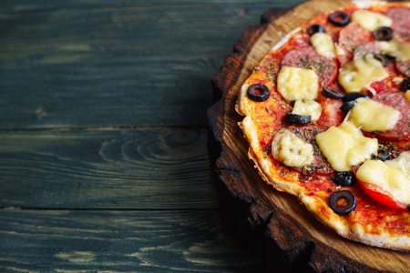 Delicious homemade pizza with salami, olives and tomatoes on theの写真素材