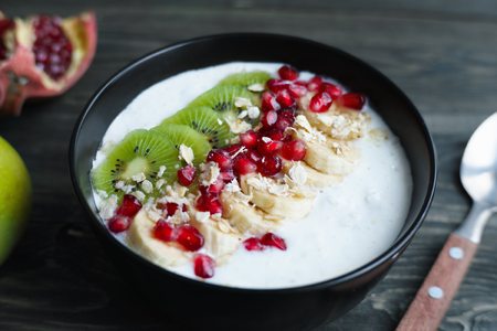 Yoghurt smoothie bowl with kiwi and banana slices, oatmeal and pの写真素材