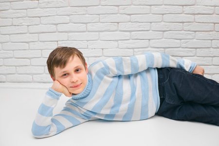 Cute boy lying on the floor of his room and props his head withの写真素材