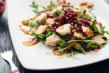 Appetizing chicken salad with pomegranate seeds and arugula on wの写真素材