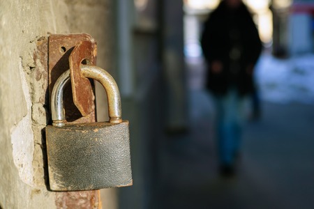 Old iron padlock hanging at open gateの写真素材