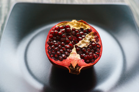 Juicy sweet ripe pomegranate on black plate, close up. Fruit, kiの写真素材