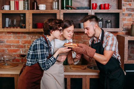 Three friends enjoy smell of freshly baked pizzaの写真素材