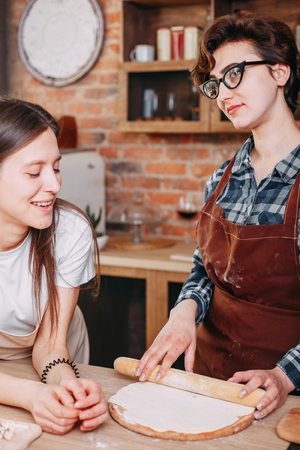 Two women friends cooking dinner and talking at domestic kitchenの写真素材