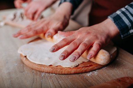 Female hands kneading pizza dough, close upの写真素材