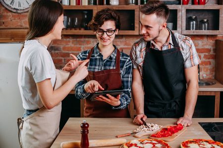 Cheerful young people reading recipe on tablet pc. Friends havinの写真素材