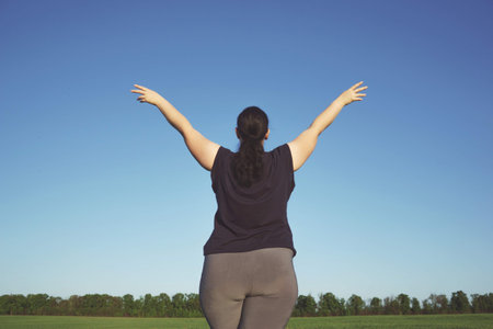 Overweight woman rising hands towards the sky