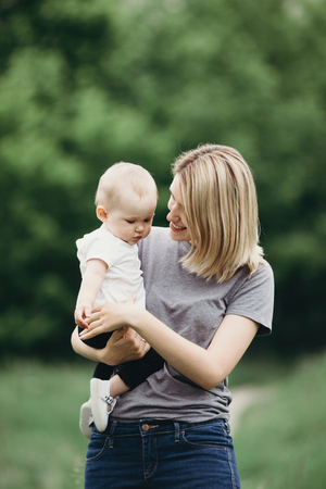 Portrait of cute baby hugging with cheerful young smiling motherの写真素材
