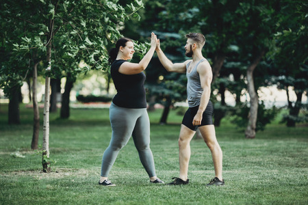 Plus size woman shaking arm of personal trainerの写真素材