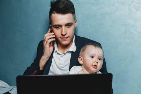 Businessman working at home watching baby daughterの写真素材