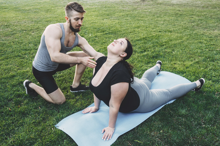 Obese woman doing yoga with instructor supportの写真素材