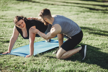 Obese woman doing exercise with instructor supportの写真素材