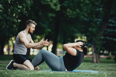 Personal trainer assisting obese woman exercisingの写真素材