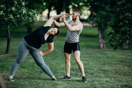 Fat woman doing yoga with fitness instructorの写真素材