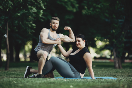 Muscular man and obese woman at street workoutの写真素材