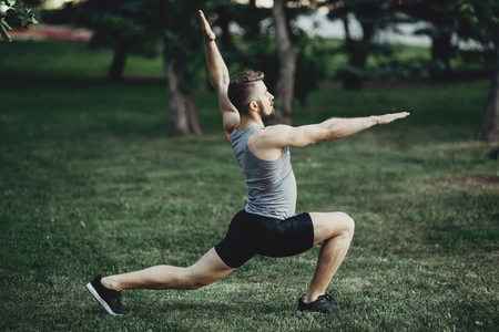 Muscular fit man doing yoga in morning parkの写真素材