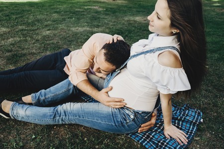 Father hearing his son kicking inside mother bellyの写真素材