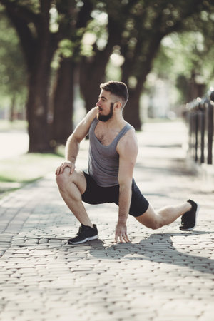 Sportsman warming up outdoors, stretching legs