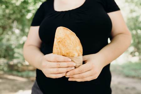Overweight woman eating fast-food walking outdoorsの写真素材