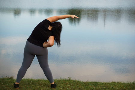 Overweight woman doing yoga in morning park