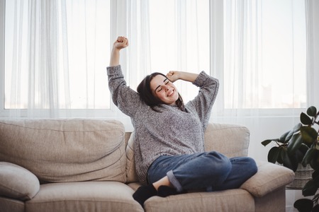 Young woman relaxing on a couch in living roomの写真素材