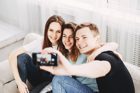 friends taking group selfie on smartphoneの写真素材
