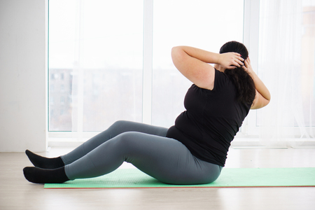 overweight woman doing crunches on mat at homeの素材 [FY310113651170]