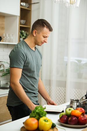 fit muscled man reading recipe book before cookingの写真素材