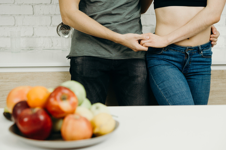 fit couple snacking with fresh fruits at kitchenの写真素材