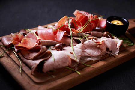 Prosciutto, ham and meat delicatessen on boardの写真素材