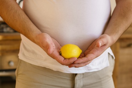 Vegetarian overweight man with lemon in handsの写真素材