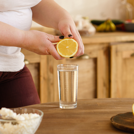 Overweight woman squeezing lemon juice into waterの写真素材
