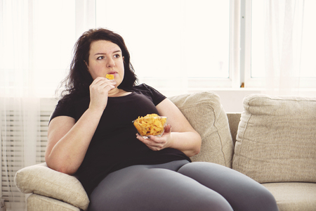 Fat woman overeating junk food.の写真素材