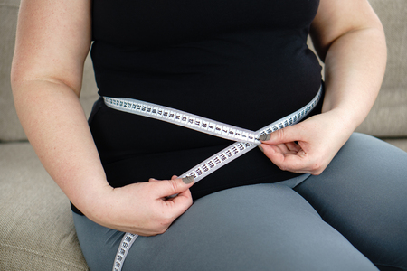 Overweight , diet. fat woman with measuring tapeの写真素材