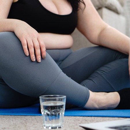 Overweight woman drink water. home yoga workoutの写真素材