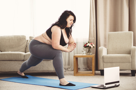 Overweight woman doing yoga workout at homeの写真素材