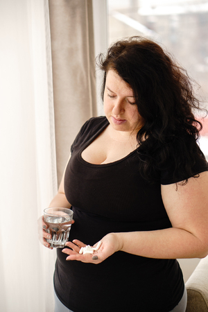 Desperate fat woman taking pills. weight lossの写真素材