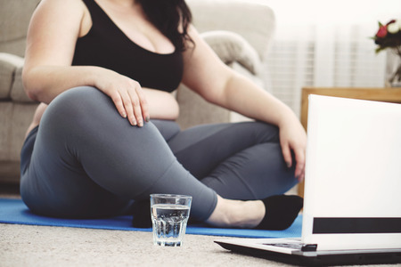 Overweight woman drink water. home yoga workoutの写真素材