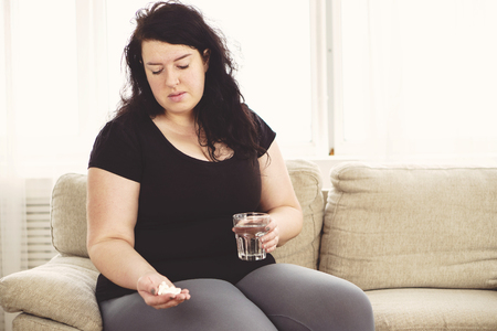 Desperate fat woman taking pills. weight lossの写真素材