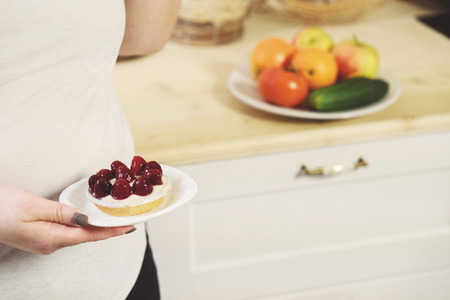Overweight woman fighting temptation to eat cakeの写真素材
