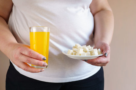 Sugar content in fruit juice and sweet carbonated drinks with stack of cubic sugar.