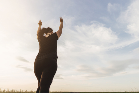 Overweight woman rising hands to the skyの写真素材