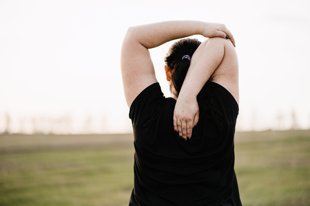 Plus-size woman stretching hands relaxing outdoorsの写真素材