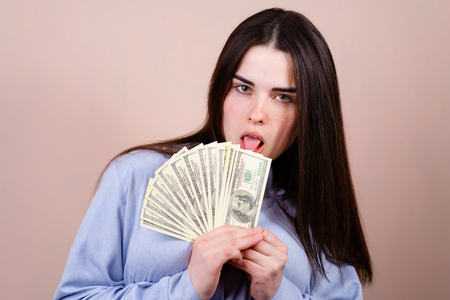 woman joyfully holding in her hand lot of dollarsの写真素材