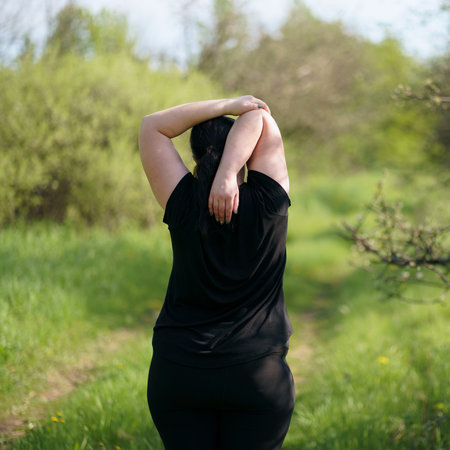 Plus-size woman stretching hands relaxing outdoors