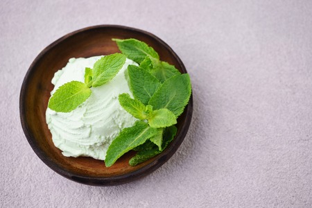 Mint ice cream scoop and peppermint leaves on stone table, copy space.の写真素材