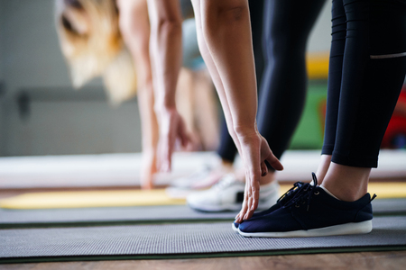 Flexibility, activity, yoga, pilates, warming up concept. Women hands stretching to toecaps on group workoutの写真素材