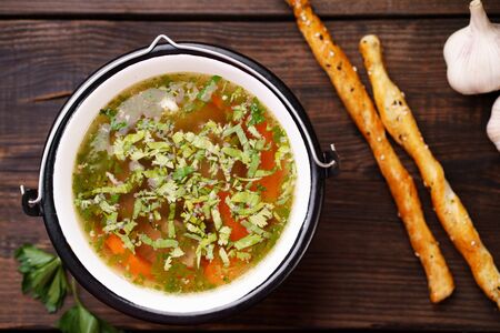 Homemade chicken vegetable soup on a rustic wooden  and bread sticks, healthy tasty nourishing mealの写真素材