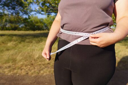 Overweight woman measuring her bellyの写真素材